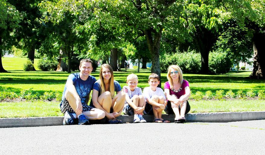 rodina sedící na kraji cesty u trávníku a parku